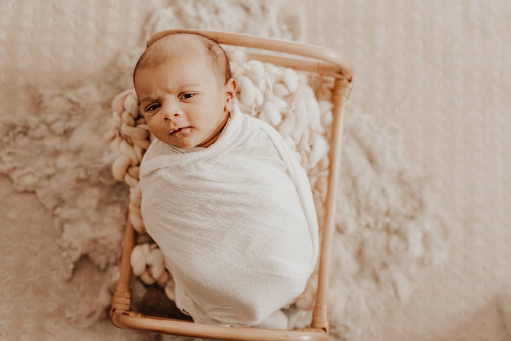 frowning baby in rattan bed