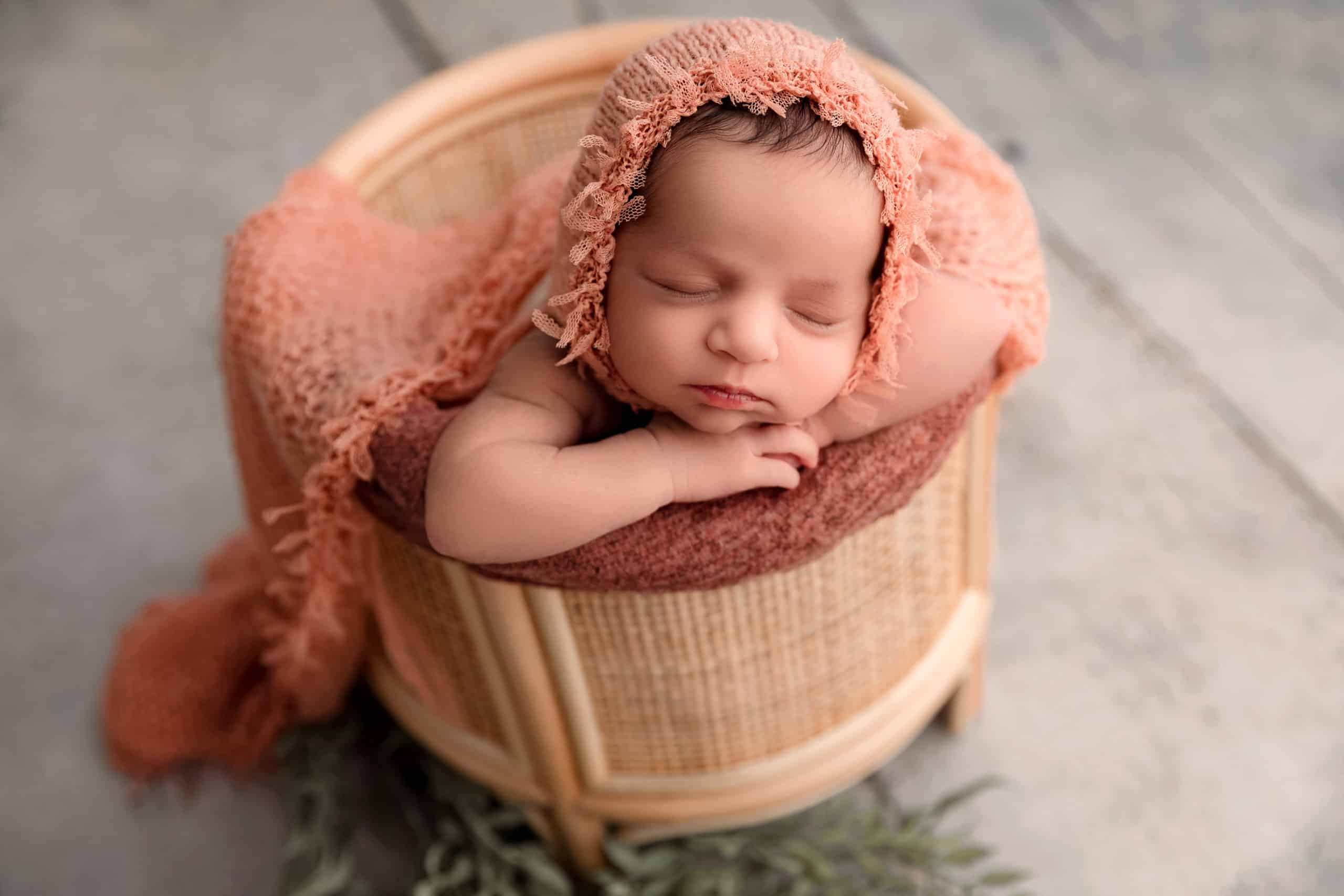 newborn girl in rattan basket pose